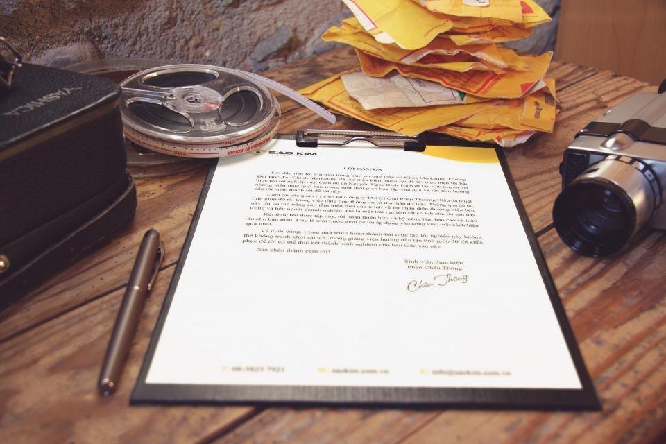 Documento firmado sobre un portapapeles junto a sobres y una pluma