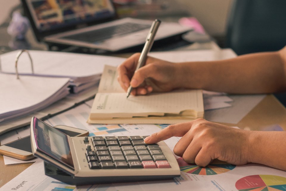 Persona haciendo cuentas con una calculadora mientras anota en una libreta