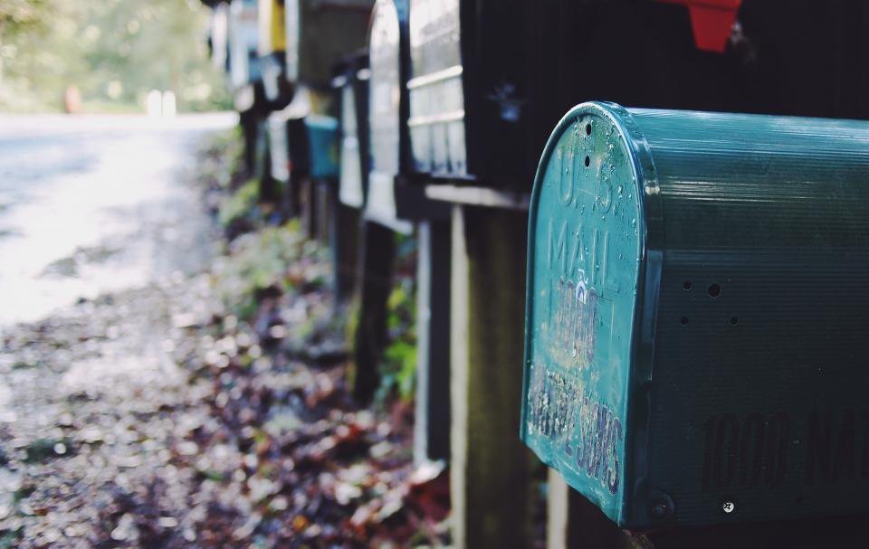 Buzón de correo metálico junto a un camino